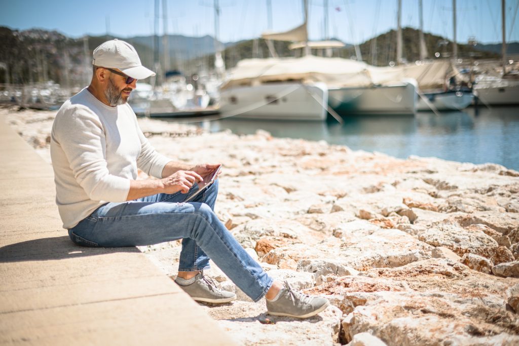 mature adult man walks along the marina with yachts