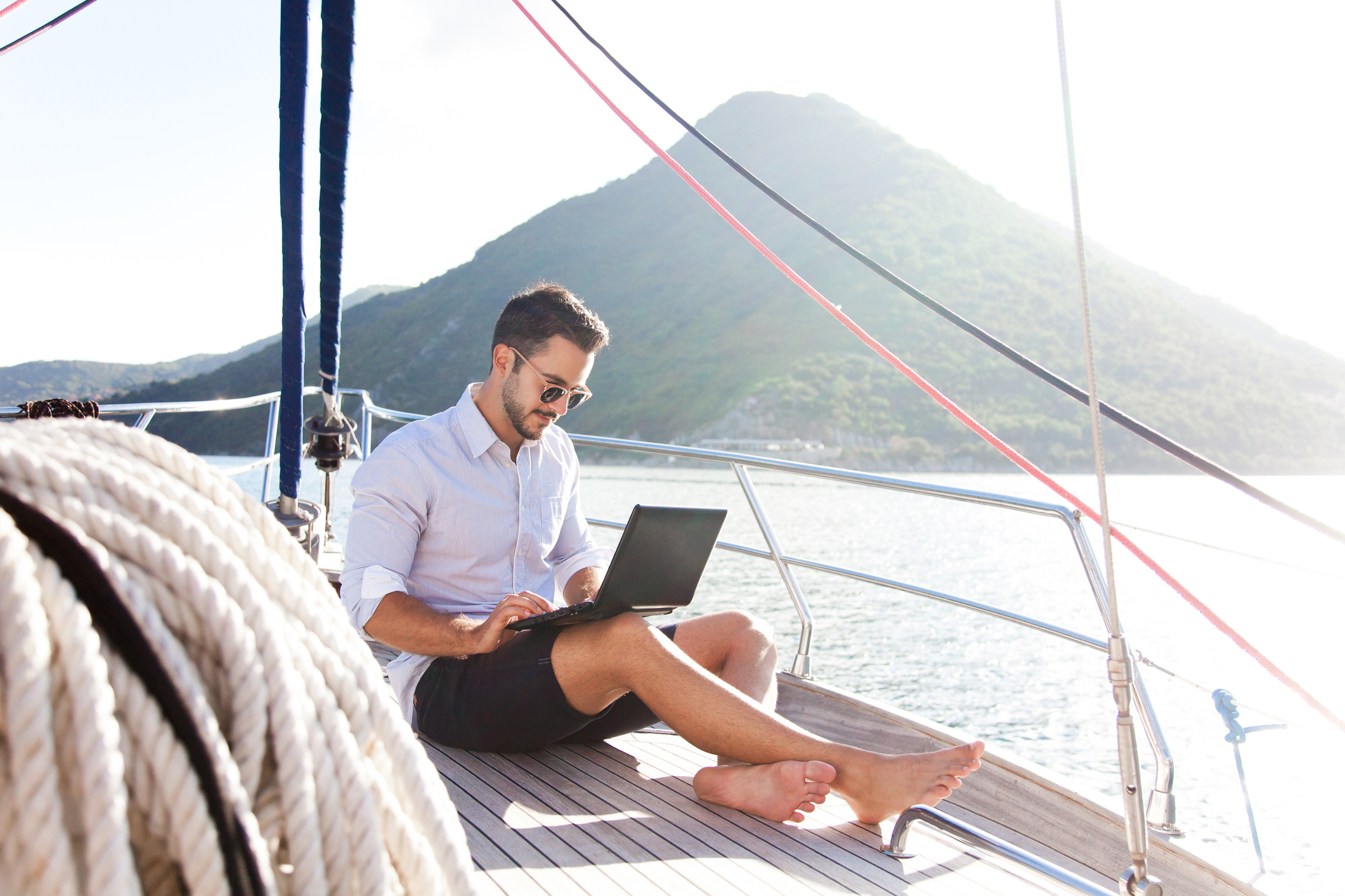 Man working on yacht office with laptop. Traveling on sailboat. Traveler using tablet computer. Freelancer workplace in self isolation, social distance. Successful business lifestyle.